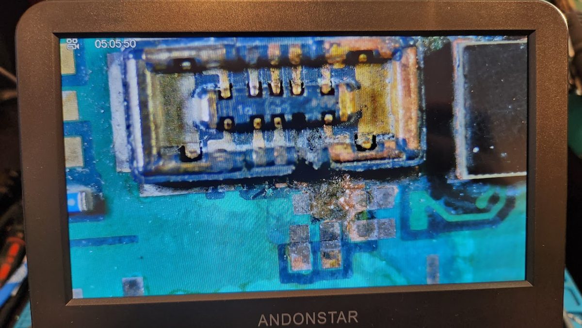 Water-damaged logic board under the microscope showing corrosion