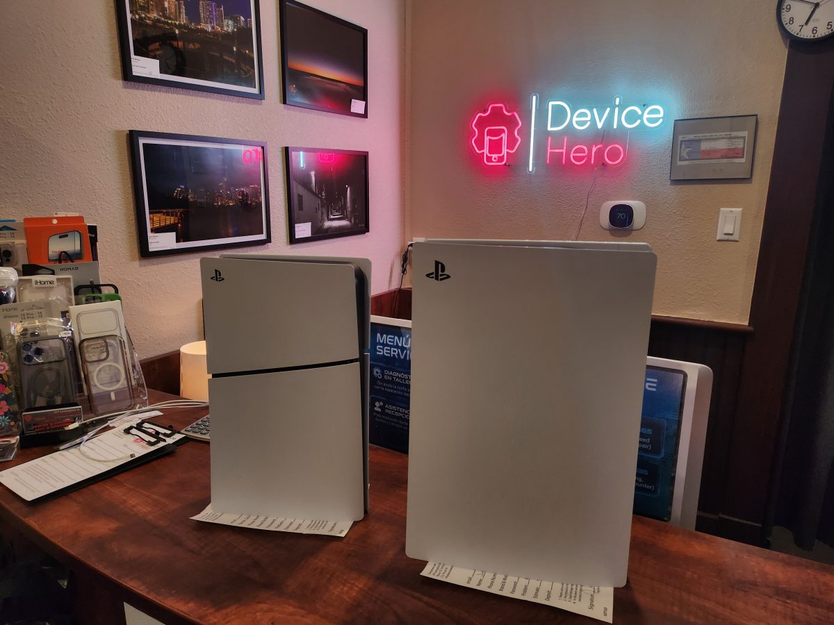 Two PlayStation 5 consoles at Device Hero's Manor, TX repair shop under the neon sign