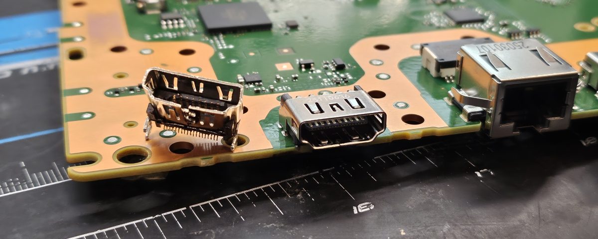 Broken HDMI port next to its new replacement on a PS5 motherboard at Device Hero in Manor, TX