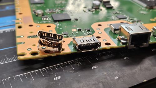 Broken HDMI port next to its new replacement on a PS5 motherboard at Device Hero in Manor, TX